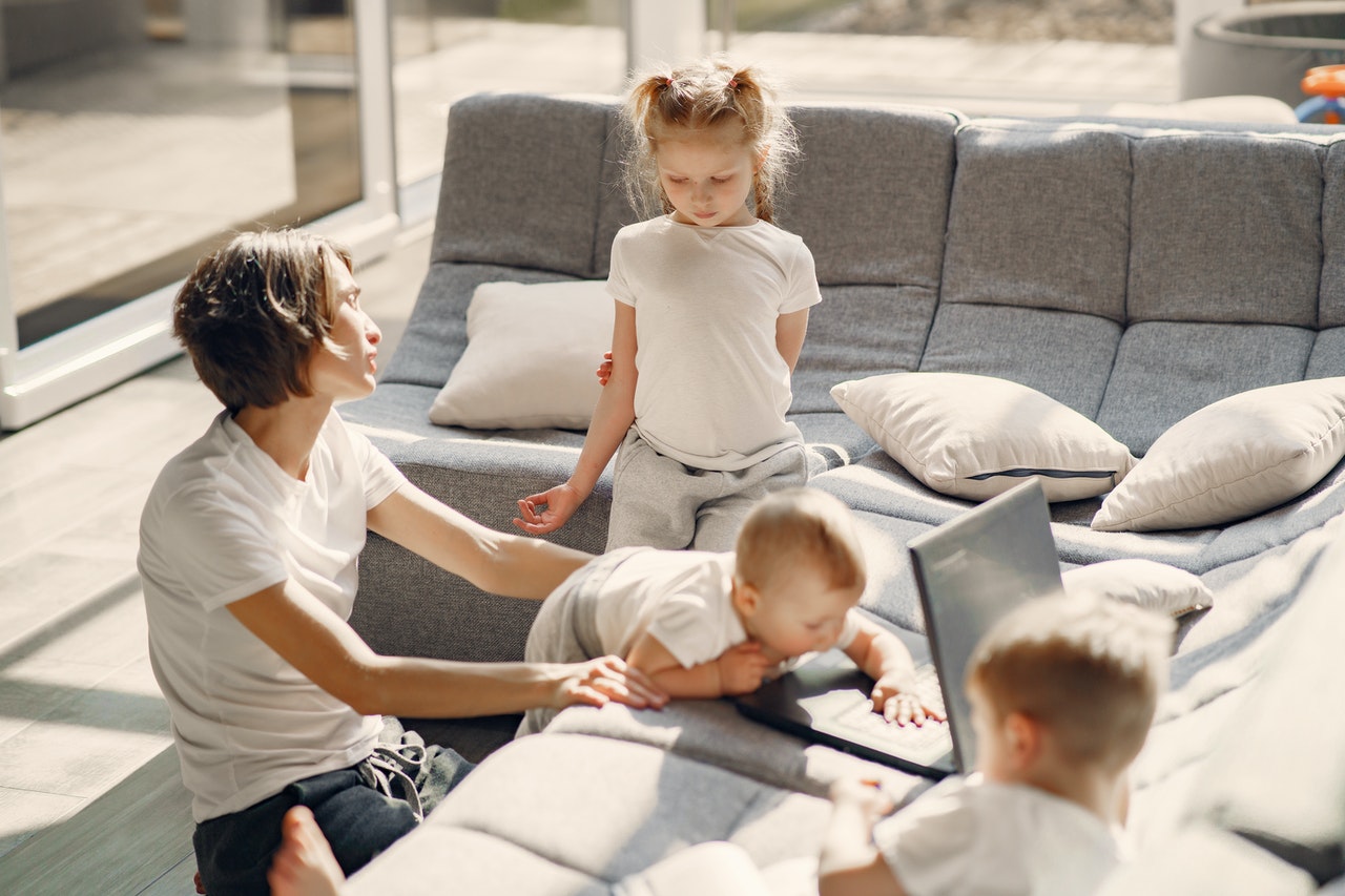 Powrót do pracy po urlopie macierzyńskim - Mama z trójką dzieci bawi się na podłodze